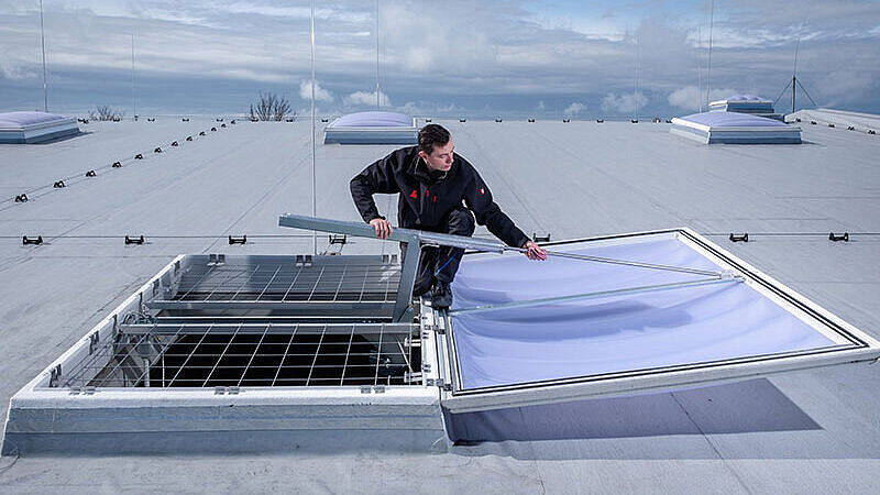 Nie odkładaj remontu dachu hali przemysłowej Dwóch monterów podczas konserwacji kopuły świetlika na hali produkcyjnej