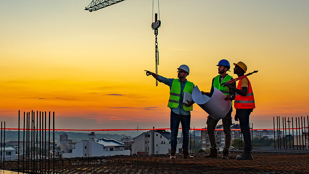 Spotkanie budowlane specjalistów remontowych w sprawie renowacji dachu płaskiego Specjaliści od renowacji LAMILUX spotykają się na budowie z płaskim dachem, omawiając projekt